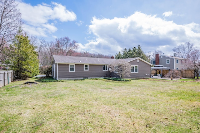 rear view of house with a patio, a yard, a chimney, a gazebo, and fence