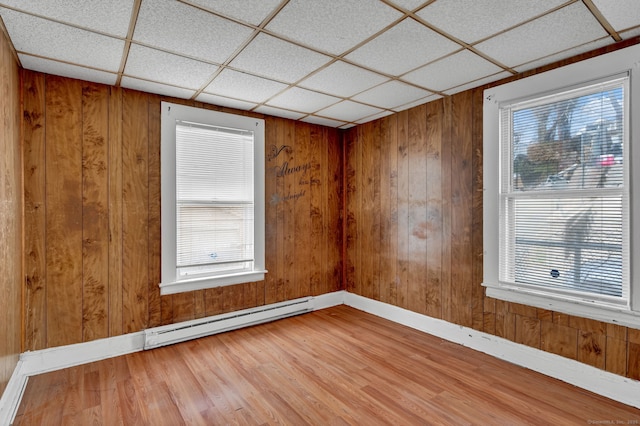 36 Gilbert St, Waterbury, CT 06702 - spare room featuring a baseboard heating unit, baseboards, wooden walls, a drop ceiling, and wood finished floors