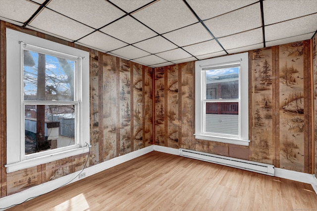 36 Gilbert St, Waterbury, CT 06702 - unfurnished room with light wood-type flooring, baseboards, a drop ceiling, wood walls, and a baseboard radiator