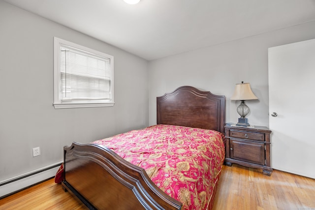 bedroom featuring a baseboard heating unit and wood finished floors