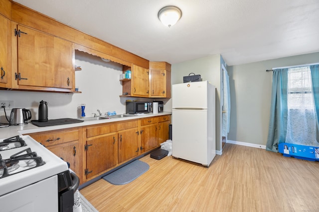 kitchen featuring a sink, light countertops, light wood-type flooring, white appliances, and brown cabinetry