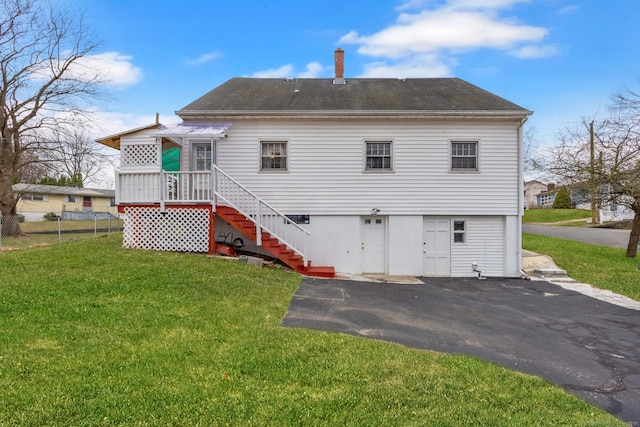 back of property with driveway, stairway, a shingled roof, and a lawn