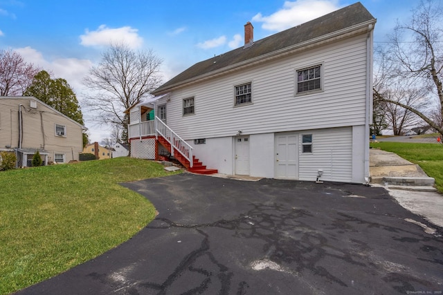 rear view of house featuring a yard, aphalt driveway, stairway, and a chimney
