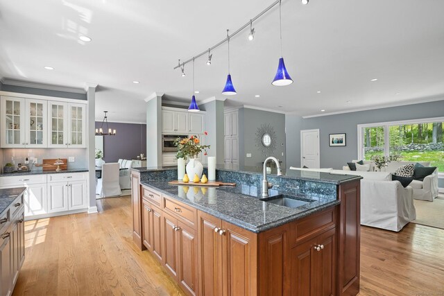 211 Linden Tree Rd, Wilton, CT 06897 - kitchen with a sink, an island with sink, light wood finished floors, crown molding, and glass insert cabinets