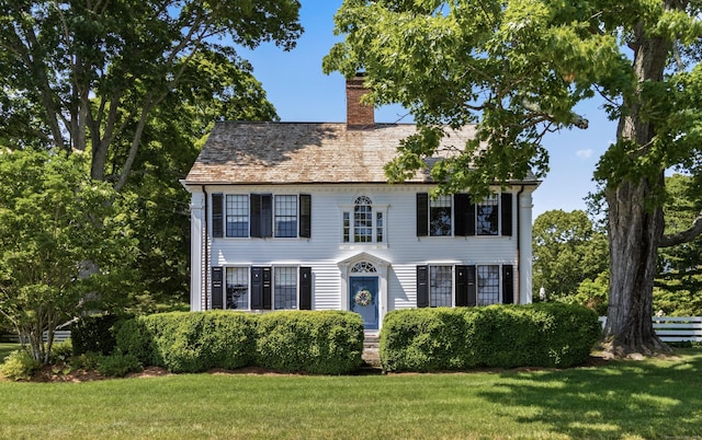 colonial house with a chimney and a front yard