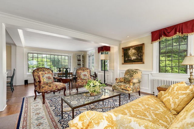 living area with radiator heating unit, crown molding, and plenty of natural light