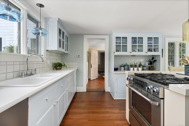 kitchen with dark wood-style floors, a sink, backsplash, gas stove, and light countertops