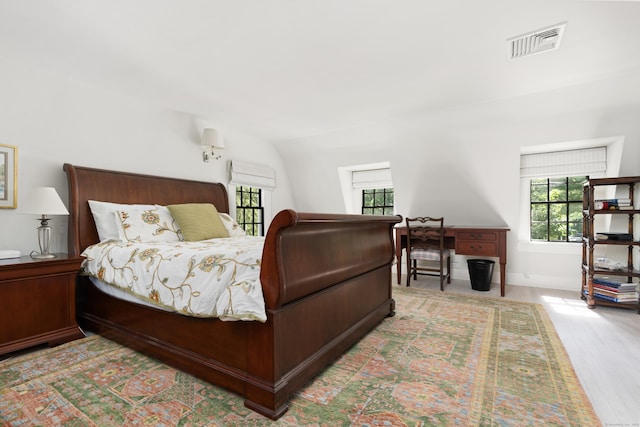 bedroom featuring wood finished floors, visible vents, baseboards, and multiple windows