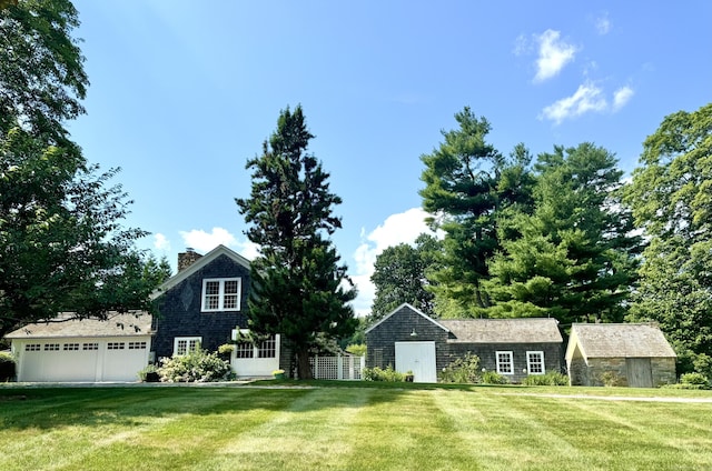 view of front of house with an outdoor structure, a front lawn, a chimney, and a garage
