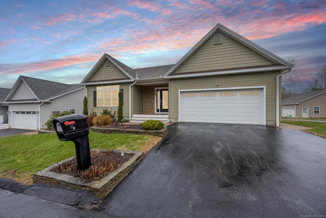 ranch-style house featuring asphalt driveway, an attached garage, and a front lawn