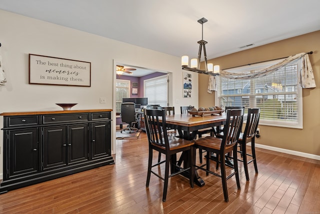 dining area with a chandelier, wood finished floors, healthy amount of natural light, and baseboards