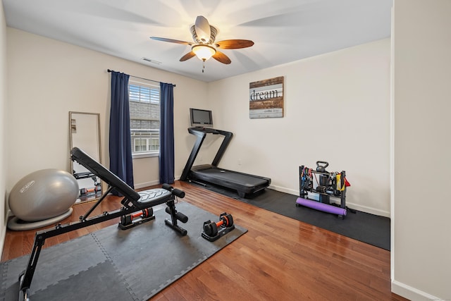 exercise area with a ceiling fan, wood finished floors, and baseboards