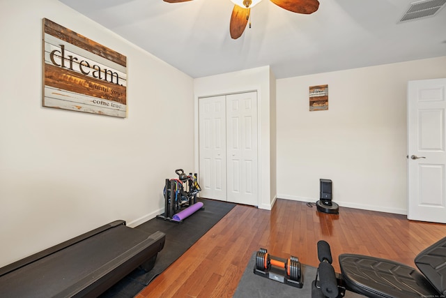 workout room with ceiling fan, hardwood / wood-style flooring, and baseboards