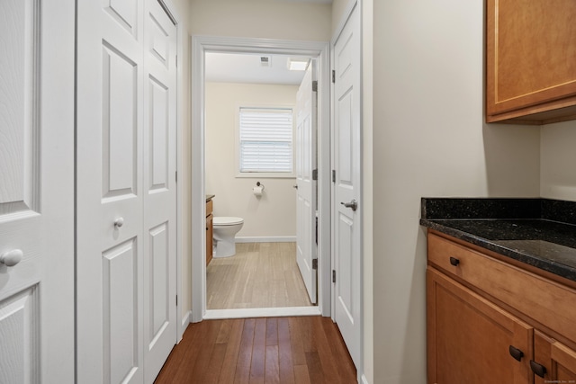 hall featuring dark wood-style flooring and baseboards