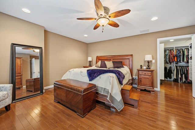 bedroom with wood finished floors, a ceiling fan, recessed lighting, a spacious closet, and baseboards