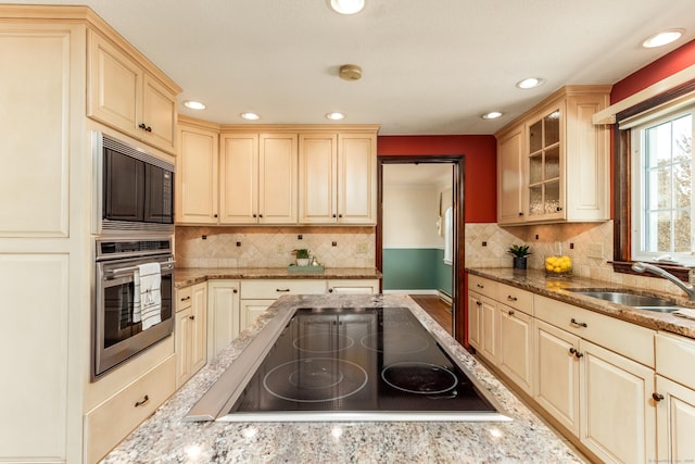 14 Valley View Dr, Wallingford, CT 06492 - kitchen with light stone countertops, a sink, black appliances, glass insert cabinets, and recessed lighting