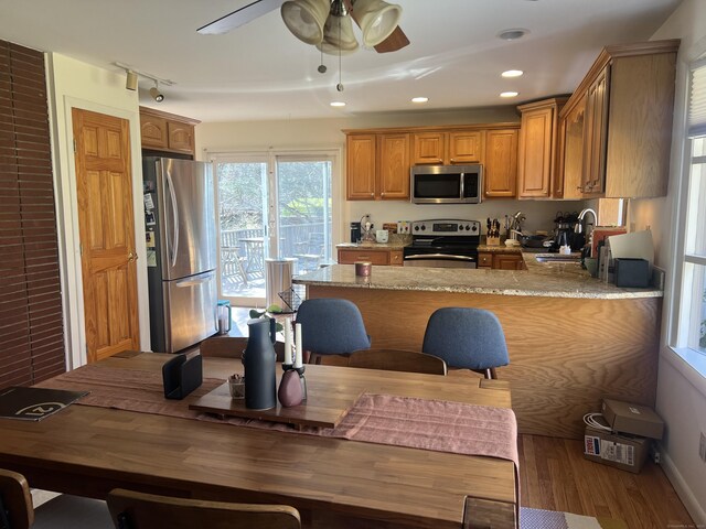 12 Fox Rd, Trumbull, CT 06611 - kitchen with appliances with stainless steel finishes, brown cabinets, wood finished floors, a peninsula, and a ceiling fan