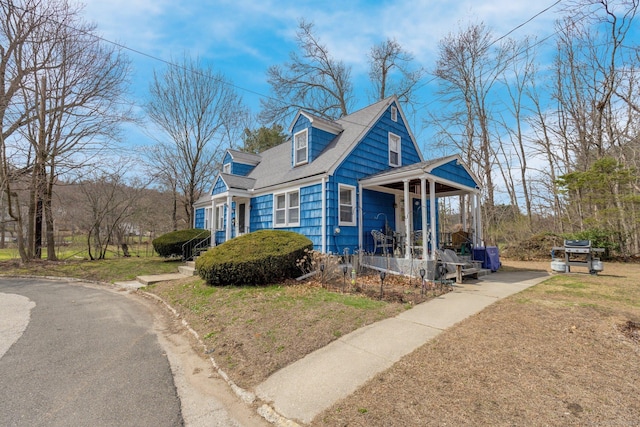 view of home's exterior with a porch and a shingled roof