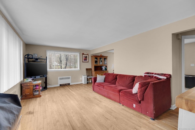 living room with radiator heating unit, baseboards, and wood finished floors