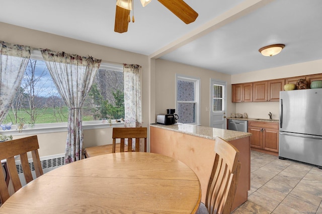 dining room featuring radiator heating unit, a ceiling fan, and a wealth of natural light