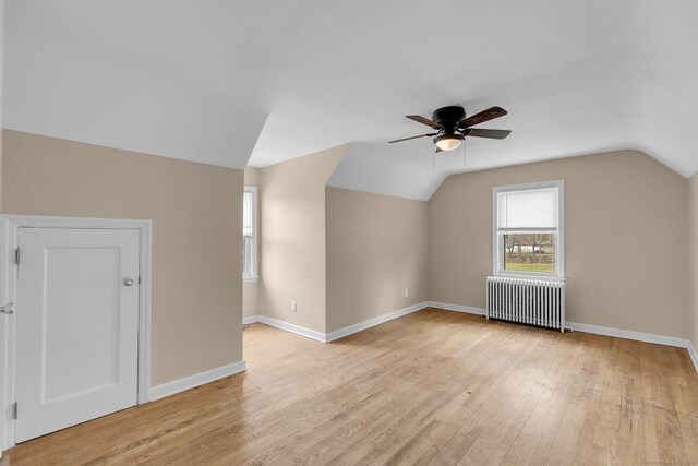 additional living space with baseboards, ceiling fan, light wood finished floors, radiator, and lofted ceiling