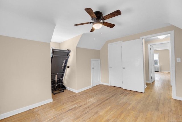 additional living space featuring radiator heating unit, light wood-type flooring, baseboards, and a ceiling fan