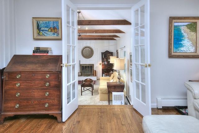interior space with beamed ceiling, baseboard heating, wood finished floors, and french doors