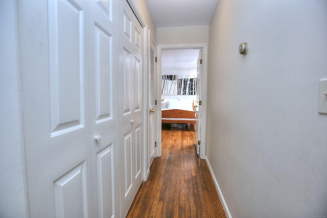 hall with baseboards and dark wood-type flooring