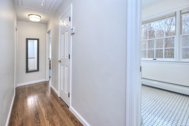 hall featuring attic access, wood finished floors, a baseboard heating unit, and baseboards