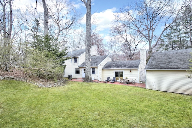 rear view of house with a patio, a chimney, and a yard