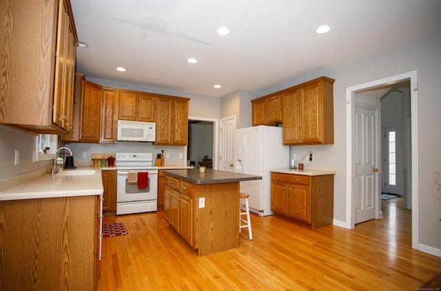 kitchen with light wood-type flooring, recessed lighting, a sink, and white appliances