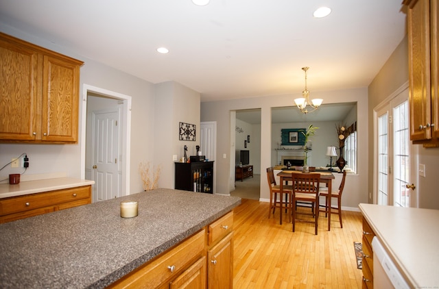 kitchen featuring light wood finished floors, recessed lighting, a chandelier, a fireplace, and brown cabinetry