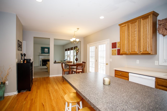 kitchen with recessed lighting, brown cabinets, a fireplace, light wood-style floors, and dishwasher