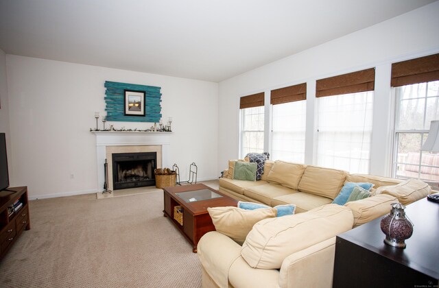 living area with baseboards, light colored carpet, a wealth of natural light, and a fireplace