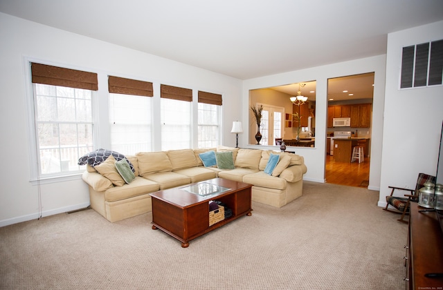 living room with an inviting chandelier, a healthy amount of sunlight, light colored carpet, and visible vents