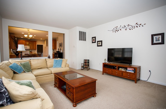 living room with a notable chandelier, baseboards, light colored carpet, and visible vents