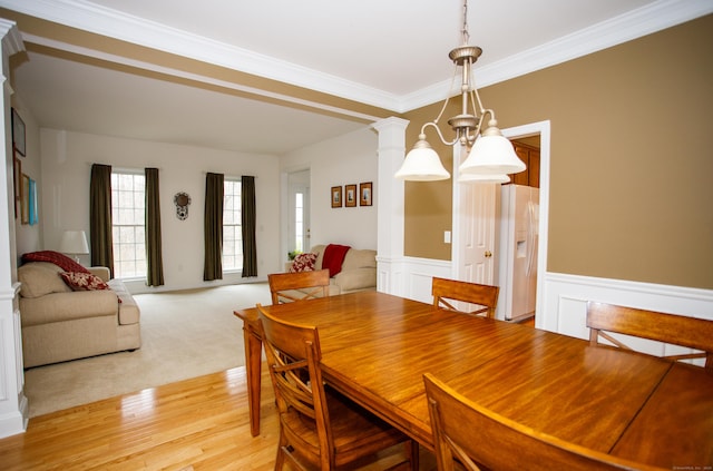 dining area featuring wainscoting, ornamental molding, and light wood-style floors