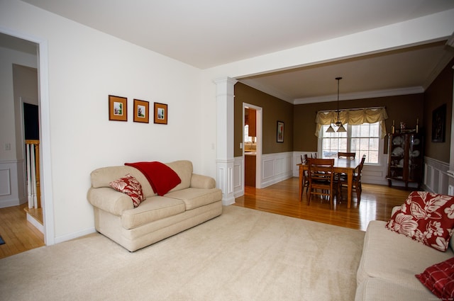 living area featuring wood finished floors, a wainscoted wall, and ornamental molding