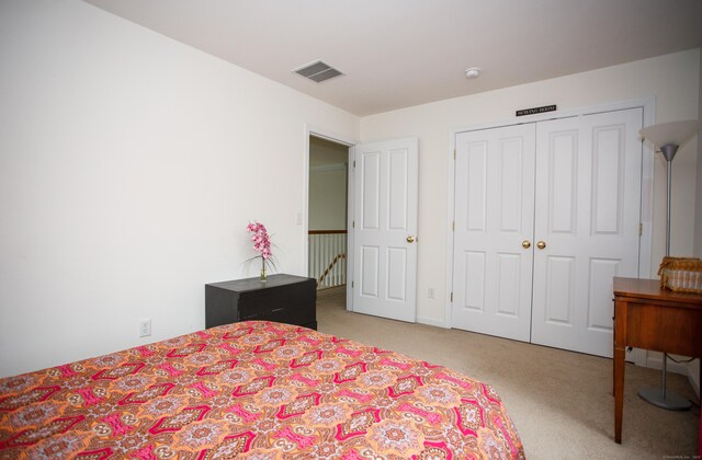 bedroom featuring a closet, visible vents, and light colored carpet
