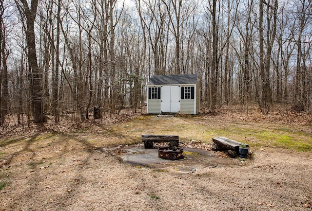 view of yard featuring a fire pit, an outdoor structure, and a shed