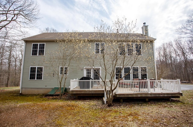 back of house with a wooden deck and a chimney