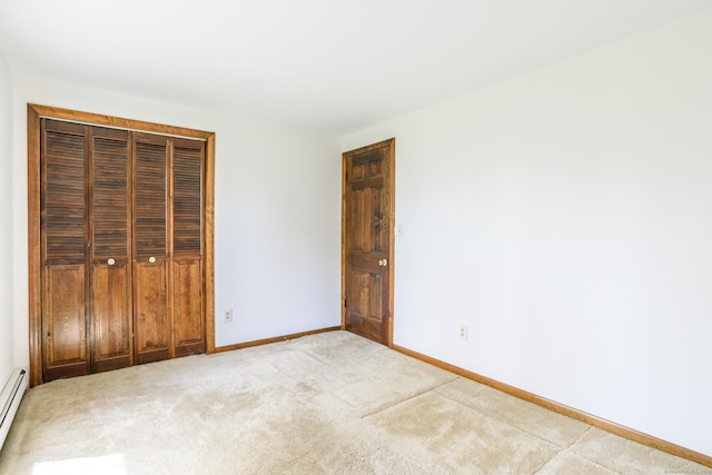 unfurnished bedroom with baseboards, light carpet, a closet, and a baseboard radiator