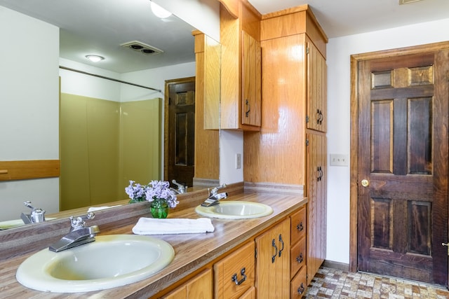 bathroom with visible vents, double vanity, and a sink