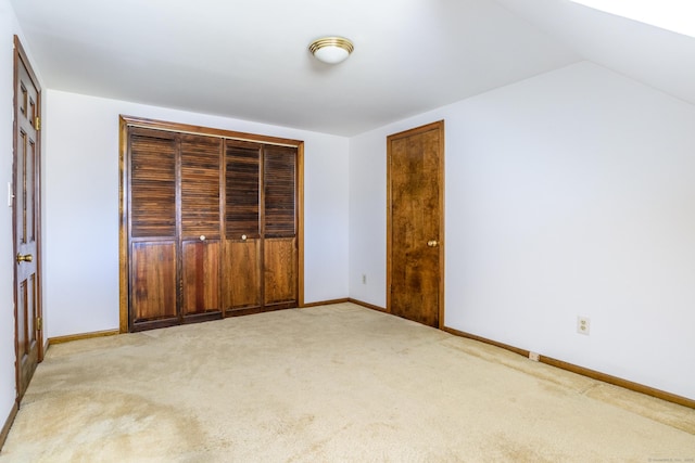 unfurnished bedroom with baseboards, carpet floors, a closet, and vaulted ceiling