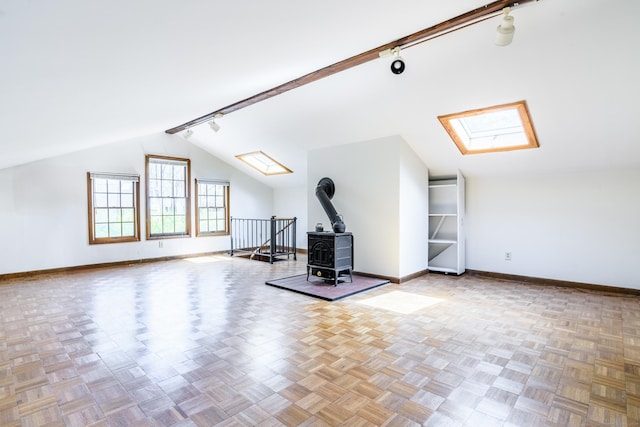 additional living space with baseboards, a wood stove, and vaulted ceiling with skylight