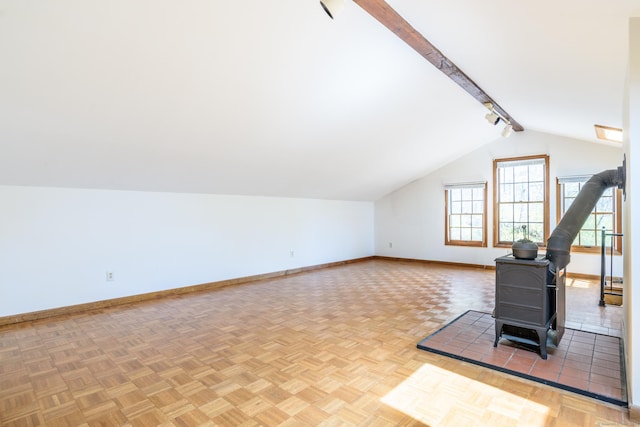 bonus room with lofted ceiling with beams, a wood stove, and baseboards