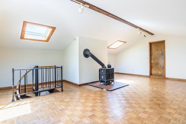 additional living space featuring a wood stove, vaulted ceiling with skylight, and baseboards