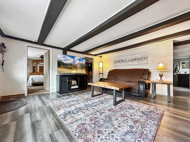 living area featuring baseboards, a ceiling fan, beam ceiling, and wood finished floors