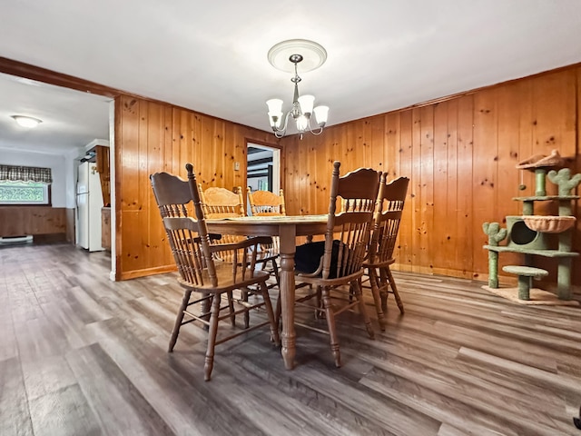 dining area featuring wood walls, wood finished floors, and a chandelier