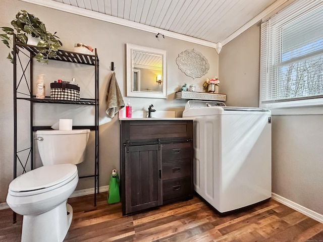 half bathroom featuring ornamental molding, wood finished floors, toilet, baseboards, and washer / clothes dryer